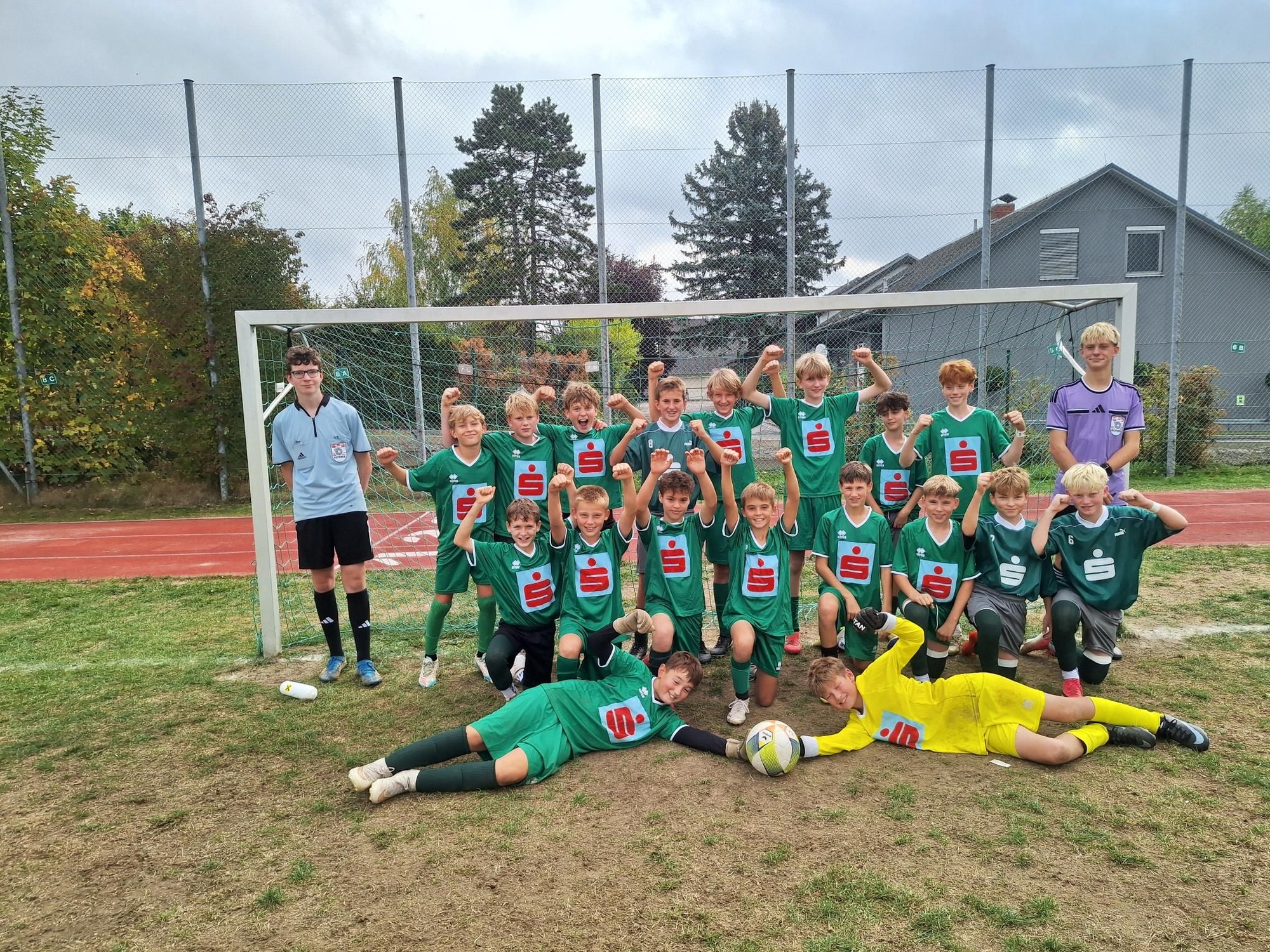 Fußballjugend in grünen Trikots mit Schiedsrichter und Torwart vor Fußballtor
